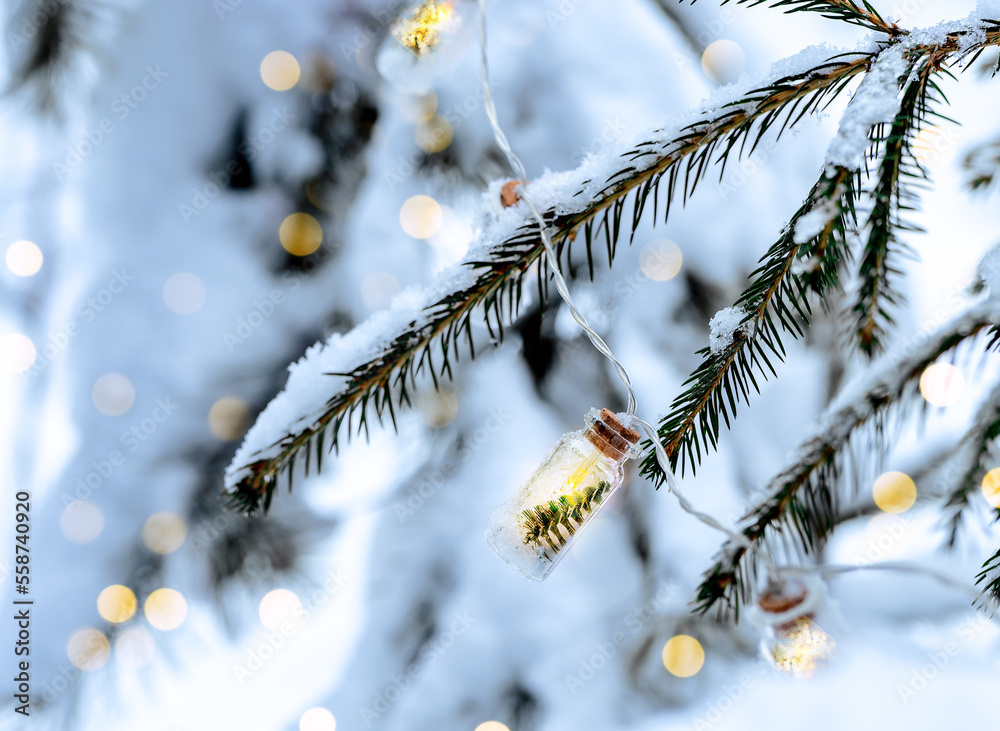 Garland lights on fir tree branches covered with snow, natural photo in forest