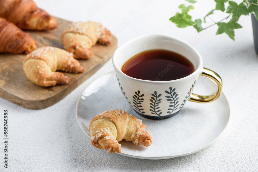 The cup of tea on a saucer and croissant The cup of tea on a saucer and croissant