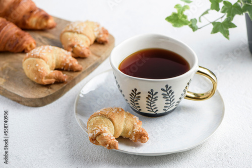 The cup of tea on a saucer and croissant photo
