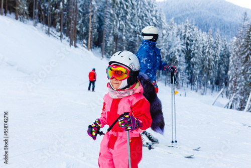 Portrait of little girl skier in sports suit finishing the ride.
