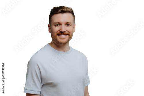 Young positive unshaven guy in white shirt has happy facial expression while looking at camera, handsome hairy man posing against blue studio background. Positive emotions concept © VK Studio