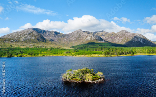 View over Lough Inagh in Connemara, Ireland, shows the prehistoric crannog, a man-made island, with Bencorr mountain of the Twelve Pins range behind