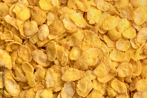 Sweet corn flakes background. Cornflakes scattered on a table. Close up top view. Breakfast for kids.