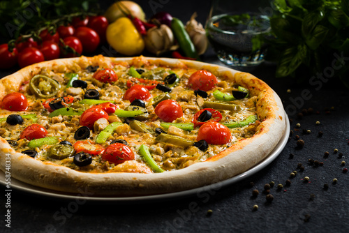 Spicy chicken pizza with olives cherry tomatoes, peppers and jalapenos