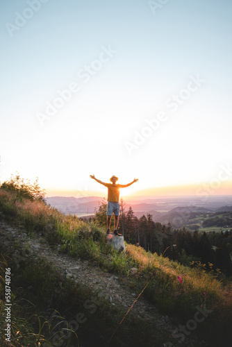 Joyful adventurer with a straw hat on his head enjoys the last touches of the sun on his journey through the countryside. Beskydy mountains, Czech republic