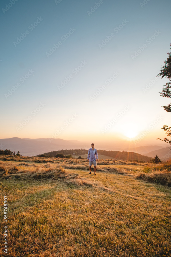 Man in shirt watching sunset on a mountain in Beskydy mountains, Czech republic. Soaking up positive energy and relieving stress. Feeling yourself