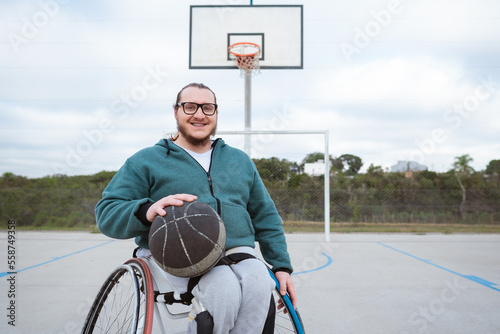 Fotografie athlete in wheelchair smiling and looking at camera with ball in basketball cour