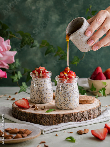 Chia and Oats pudding with almonds, strawberries and a drip of honey, over a rustic base and a napkin photo