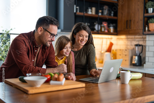 Happy family searching for delicious recipes online while standing in the kitchen.