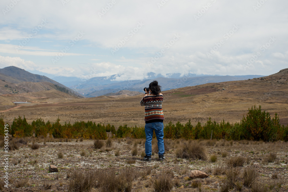 Male tourist in landscape of the Andes of South America with a camera in his hand. Concept of people, travel, tourism.
