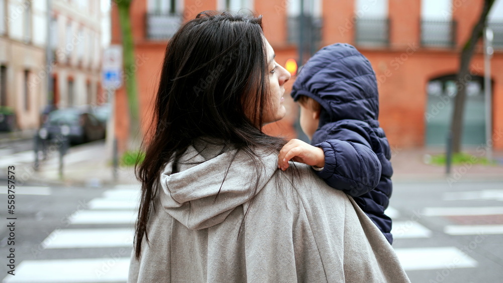 Mother holding baby toddler waiting to cross street
