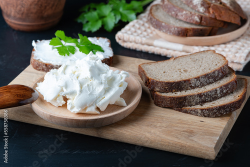 Home made bread on a wooden cutting board with curd cheese and ricotta