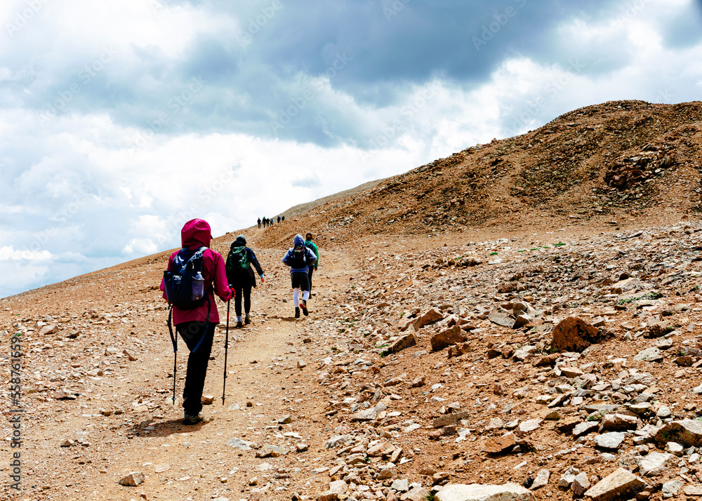 A group of Hikers climbing Mount Bross at 14,172 elevation, Park County, Colorado, on brown rocky path with overcast sky