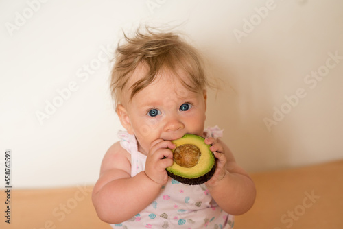 little girl eating a fruit. Little child eats an avocado