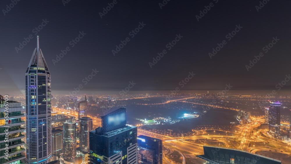 Fototapeta premium Aerial skyline with Golf Club, hotels and residential areas far away in desert in Dubai all night timelapse, UAE, top view