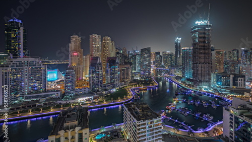 Panorama showing Dubai Marina with several boat and yachts parked in harbor and skyscrapers around canal aerial night timelapse. © neiezhmakov