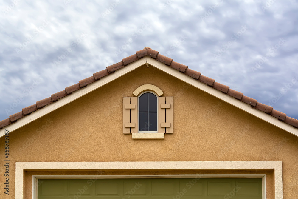 House attic gable window on stucco wall with cloudy sky background, Menifee, California House attic gable window on stucco wall with cloudy sky background, Menifee, California