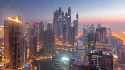 View of various skyscrapers in tallest recidential block in Dubai Marina aerial night to day timelapse