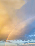 Background formed by a bright colorful sky with visible rainbow after rain. Orange, blue blur elegant backdrop with empty space perfect for design. Unique and magical landscape during the golden hour