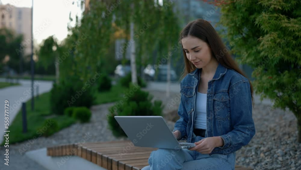 Caucasian woman sitting on the bench working on the laptop near the business centre. Female manager working, using laptop for working purposes. People and technology concept Caucasian woman sitting on the bench working on the laptop near the business centre. Female manager working, using laptop for working purposes. People and technology concept