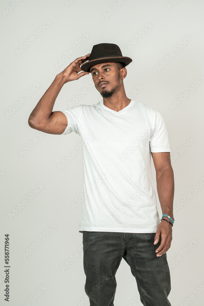 A young handsome man wearing white blank shirt, doing a simple pose with on of his hand on his hat A young handsome man wearing white blank shirt, doing a simple pose with on of his hand on his hat
