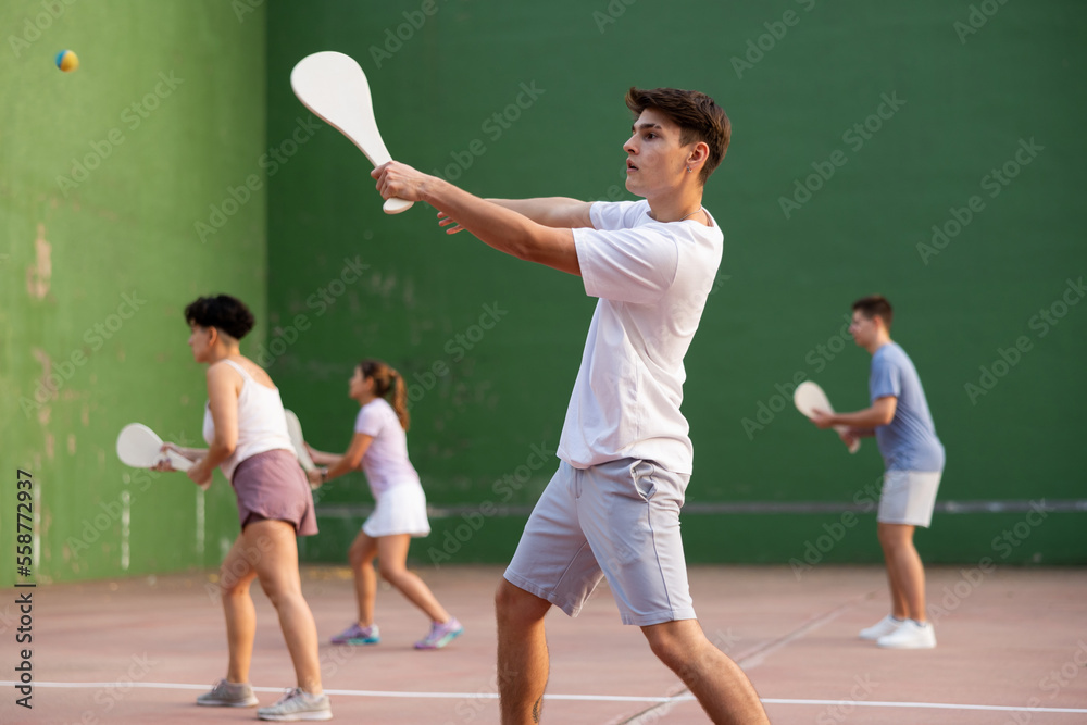 Caucasian teenage boy in sportswear playing paleta fronton on outdoor court