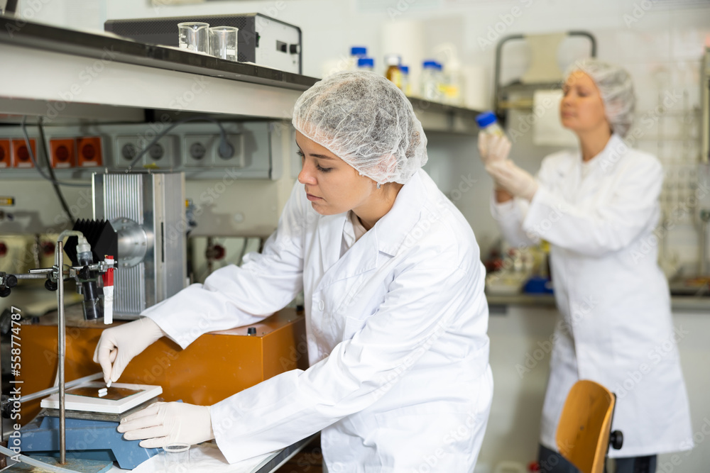 Obraz premium Female laboratory assistant weighs tablets on precision scales in a biochemical laboratory