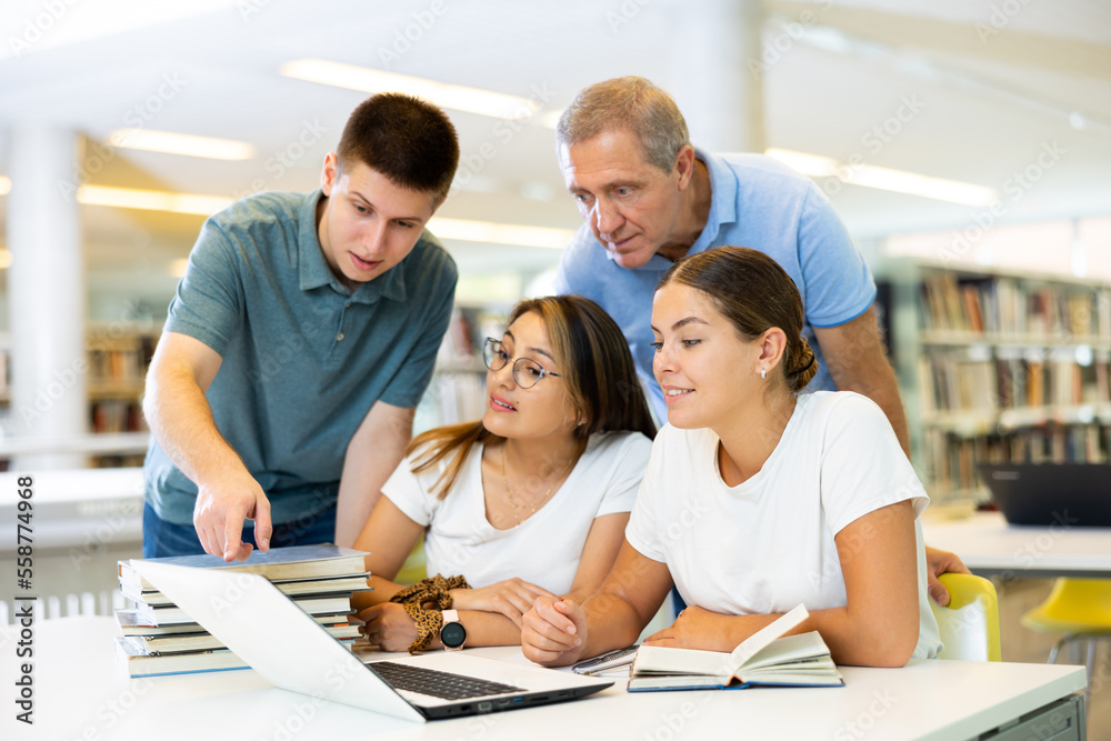 Obraz premium Group portrait of smiling positive engaged in research, working together in public library