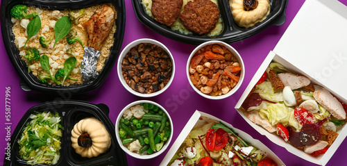 Containers with delicious food for delivery on purple background