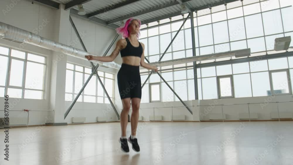 Sportswoman training in a bright studio. Woman exercising with a jumping rope, strengthening her upper body and legs. High quality 4k footage Sportswoman training in a bright studio. Woman exercising with a jumping rope, strengthening her upper body and legs. High quality 4k footage