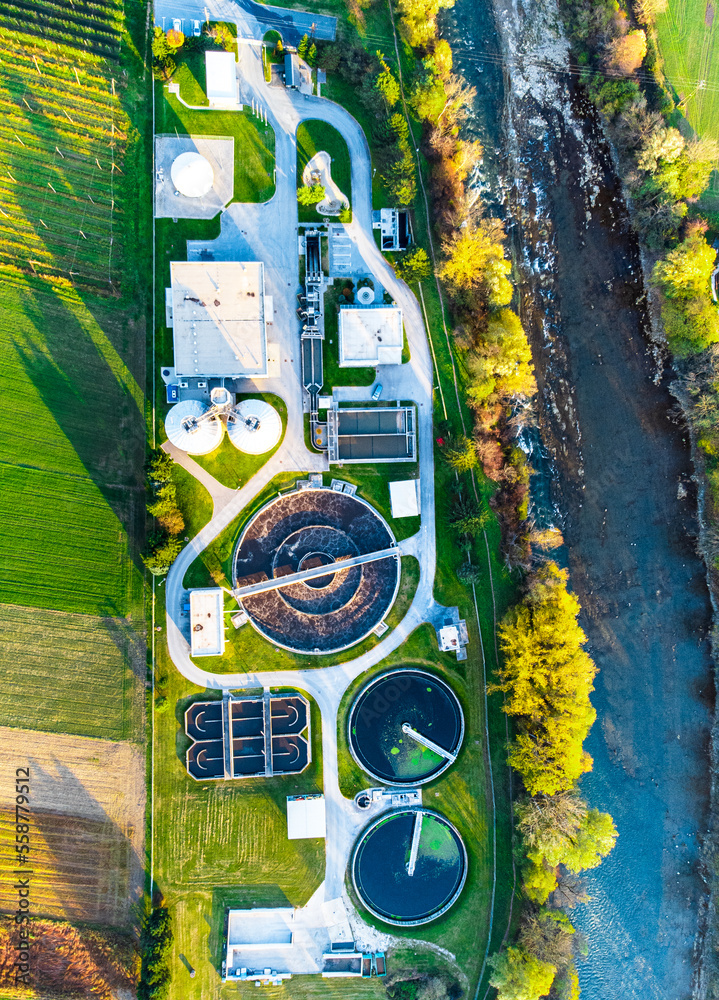 Water and sewage treatment plant lit from the afternoon sun aerial top
