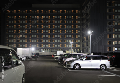 Full parking lot by multi-story hotel building at night