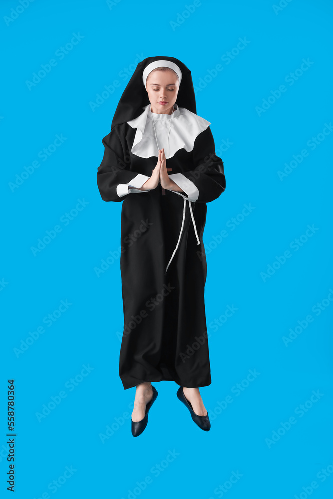 Young nun jumping on blue background Young nun jumping on blue background