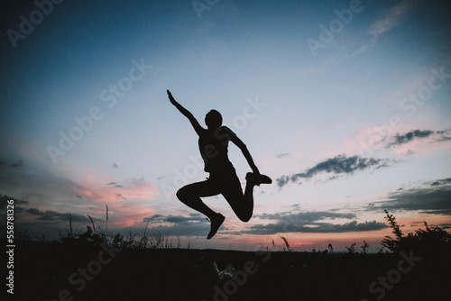 woman jumping with joy against sunset sky