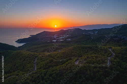 Aerial top view winding road in middle forest background sea Turkey sunset light