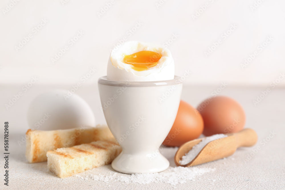 Holder with soft boiled egg, toasted bread and scoop on white table Holder with soft boiled egg, toasted bread and scoop on white table
