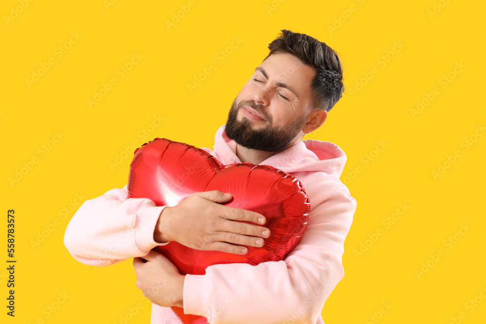 Young bearded man with balloon for Valentine's Day on yellow background Young bearded man with balloon for Valentine's Day on yellow background