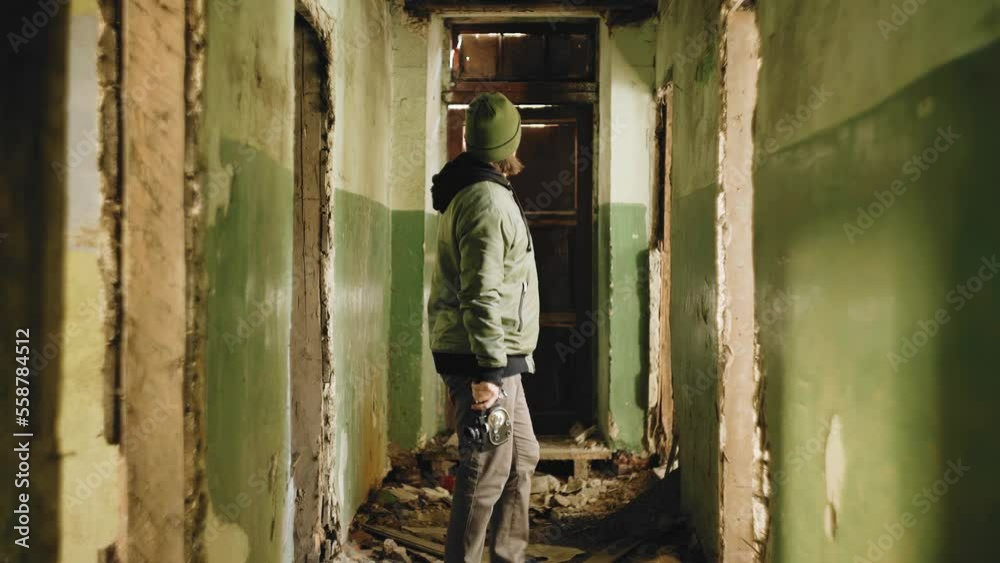 A man stands in the corridor of an old house and looks around. He is in an abandoned house A man stands in the corridor of an old house and looks around. He is in an abandoned house