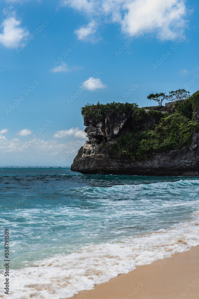 Weißer tropischer Sandstrand mit strahlend blauen Meer und einer Felsen im Hintergrund, Indonesien, Bali