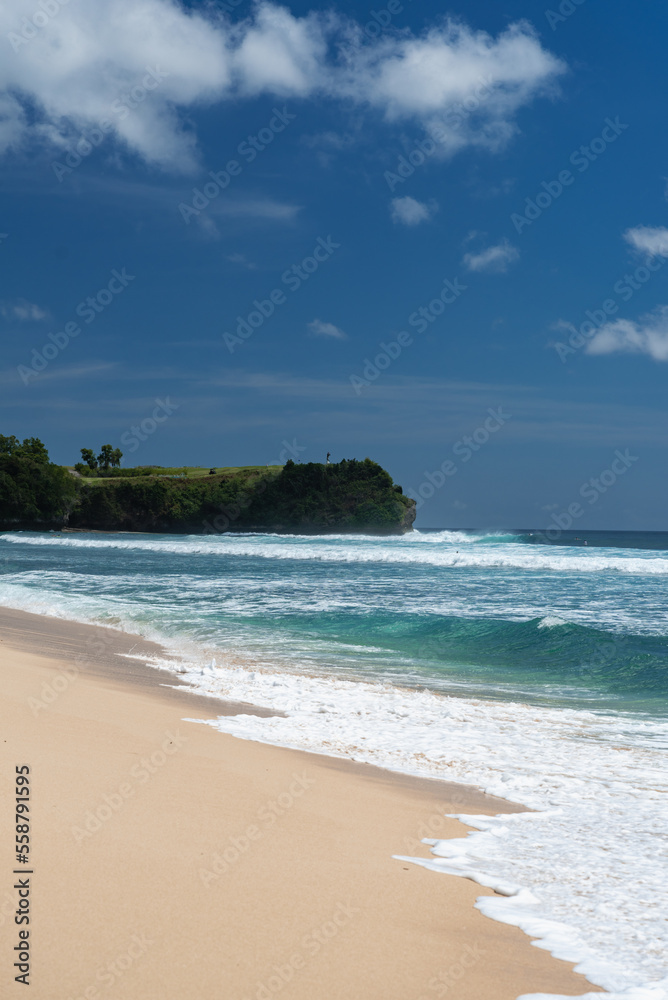 Weißer tropischer Sandstrand mit strahlend blauen Meer und einer Felsen im Hintergrund, Indonesien, Bali Weißer tropischer Sandstrand mit strahlend blauen Meer und einer Felsen im Hintergrund, Indonesien, Bali