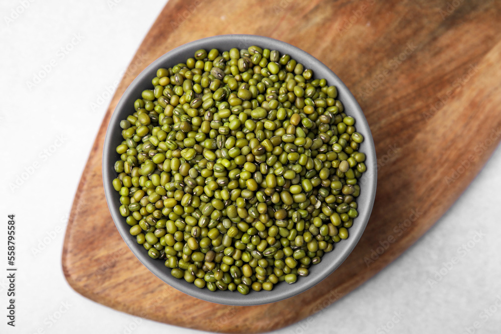 Bowl with green mung beans and wooden board on white table, top view Bowl with green mung beans and wooden board on white table, top view