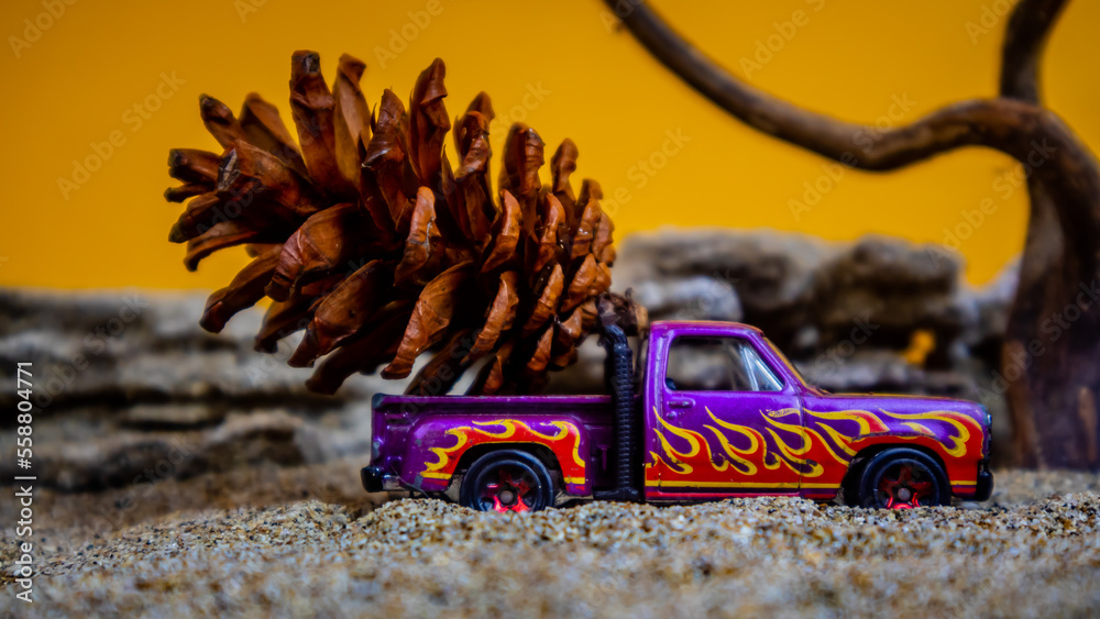 Fototapeta premium toy car hauling pinecones on an orange background