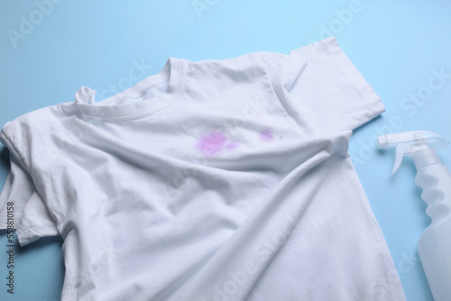 White shirt with purple stains and detergent on light blue background, above view © New Africa
