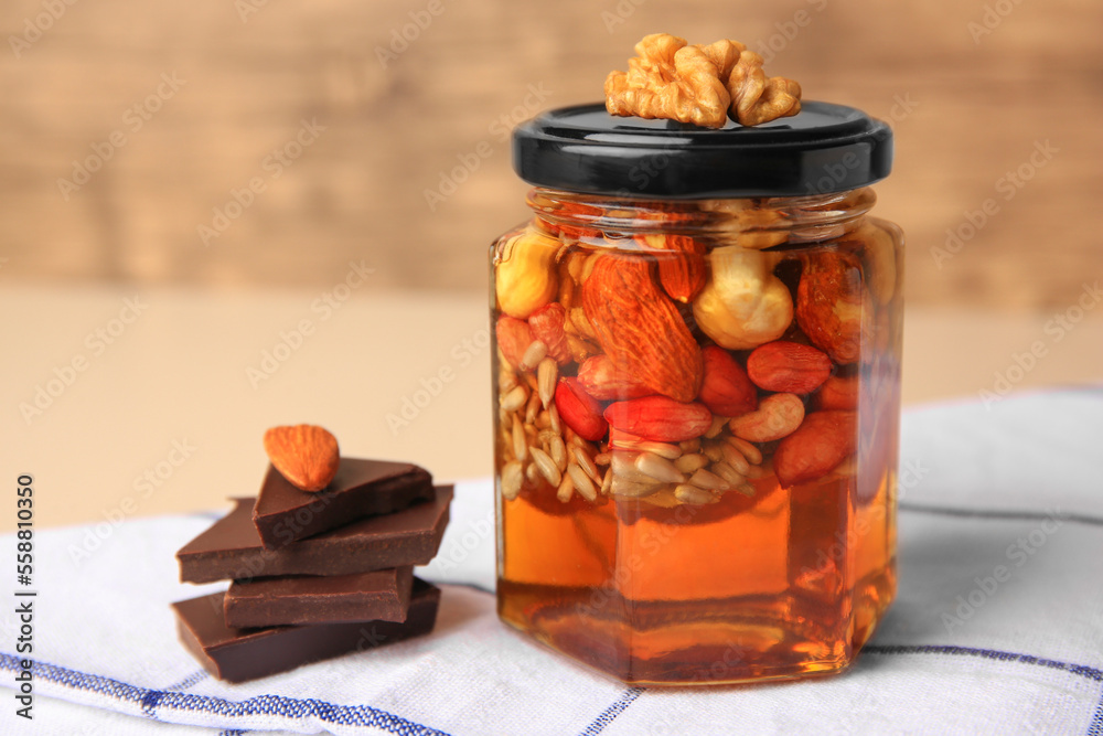 Different nuts and honey in jar, chocolate on table, closeup Different nuts and honey in jar, chocolate on table, closeup