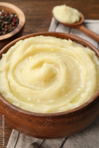 Bowl of tasty mashed potato and pepper on wooden table, closeup