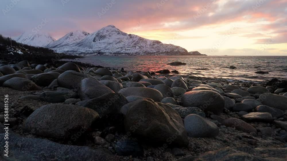 Sunset time on the beach by the Norwegian fiord. Wavy Northern Sea in setting sun colors. Amazing clouds on the sky. Sunset time on the beach by the Norwegian fiord. Wavy Northern Sea in setting sun colors. Amazing clouds on the sky.