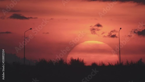 Daybreak in the morning is marked by the large sun rising gradually from above the horizon. In the winter morning, the sun rises amid a hazy or foggy sky. Dawn sunrise on the natural landscape.