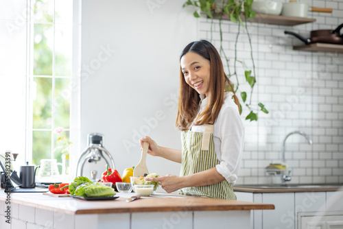 Portrait of attractive asian japanese woman in kitchen at home  young girl browsing website on tutor cooking class and doing for kitchen  cutting vegetables  cooking  cooking concept.