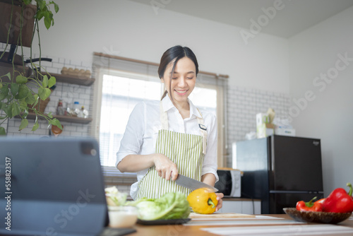 Portrait of attractive asian japanese woman in kitchen at home  young girl browsing website on tutor cooking class and doing for kitchen  cutting vegetables  cooking  cooking concept.