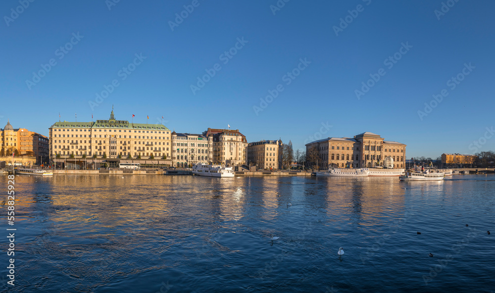 Fototapeta premium The bay Strömmen museums, moored boats and hotels on a pier a low winter solstice a sunny and snowy day in Stockholm